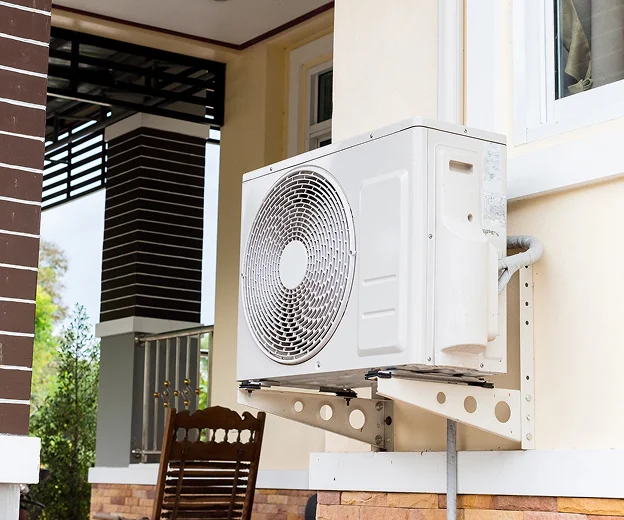 Unité extérieure de climatisation murale blanche sur une maison de couleur crème à Saint-Pathus près de Meaux en Seine-et-Marne 77