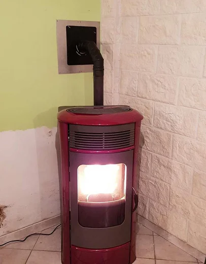 Poêle à granulés rouge ardent dans un coin, mur vert et en briques à Saint-Pathus près de Meaux en Seine-et-Marne 77