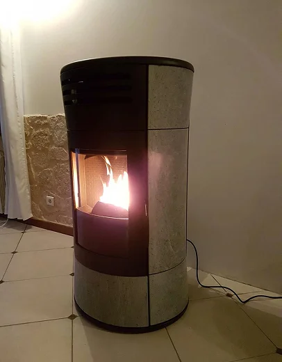 Un poêle à granulés anthracite et gris, avec des flammes lumineuses, sur un sol carrelé à Saint-Pathus près de Meaux en Seine-et-Marne 77